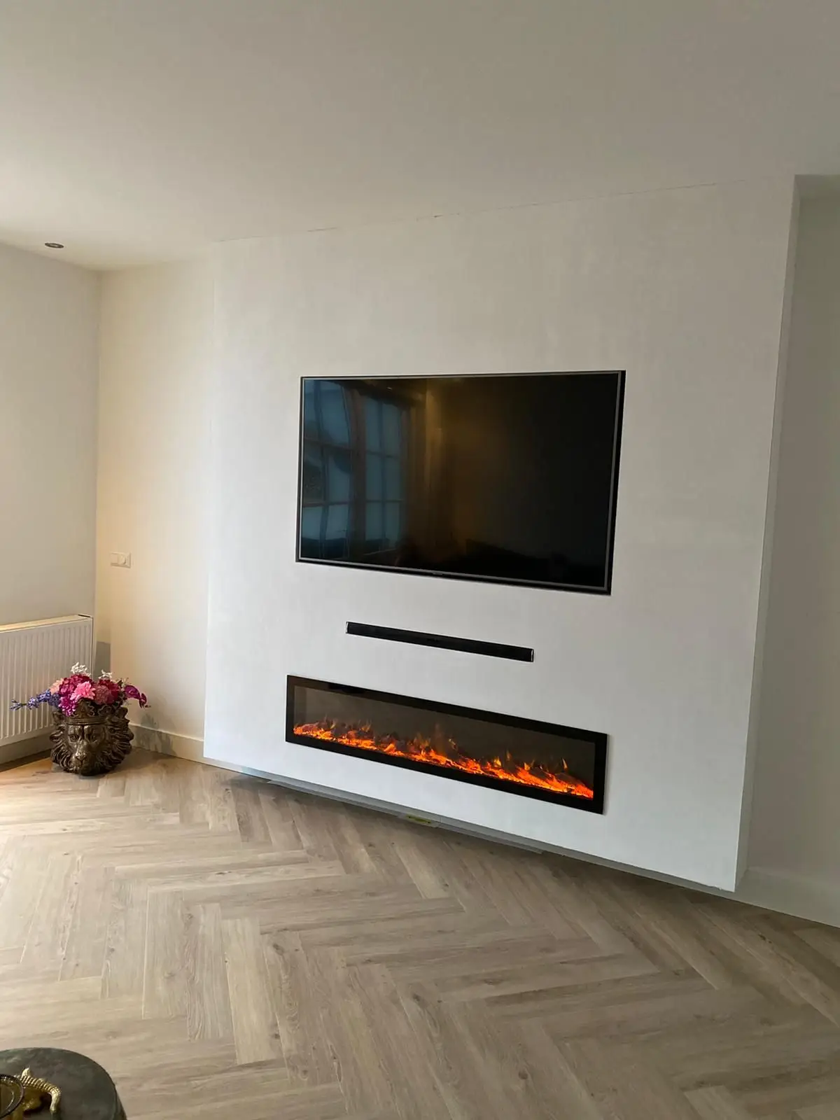 Tv-wand in lichte design stuc met ingebouwde sfeerhaard, afgewerkt door Onkel Stukadoors