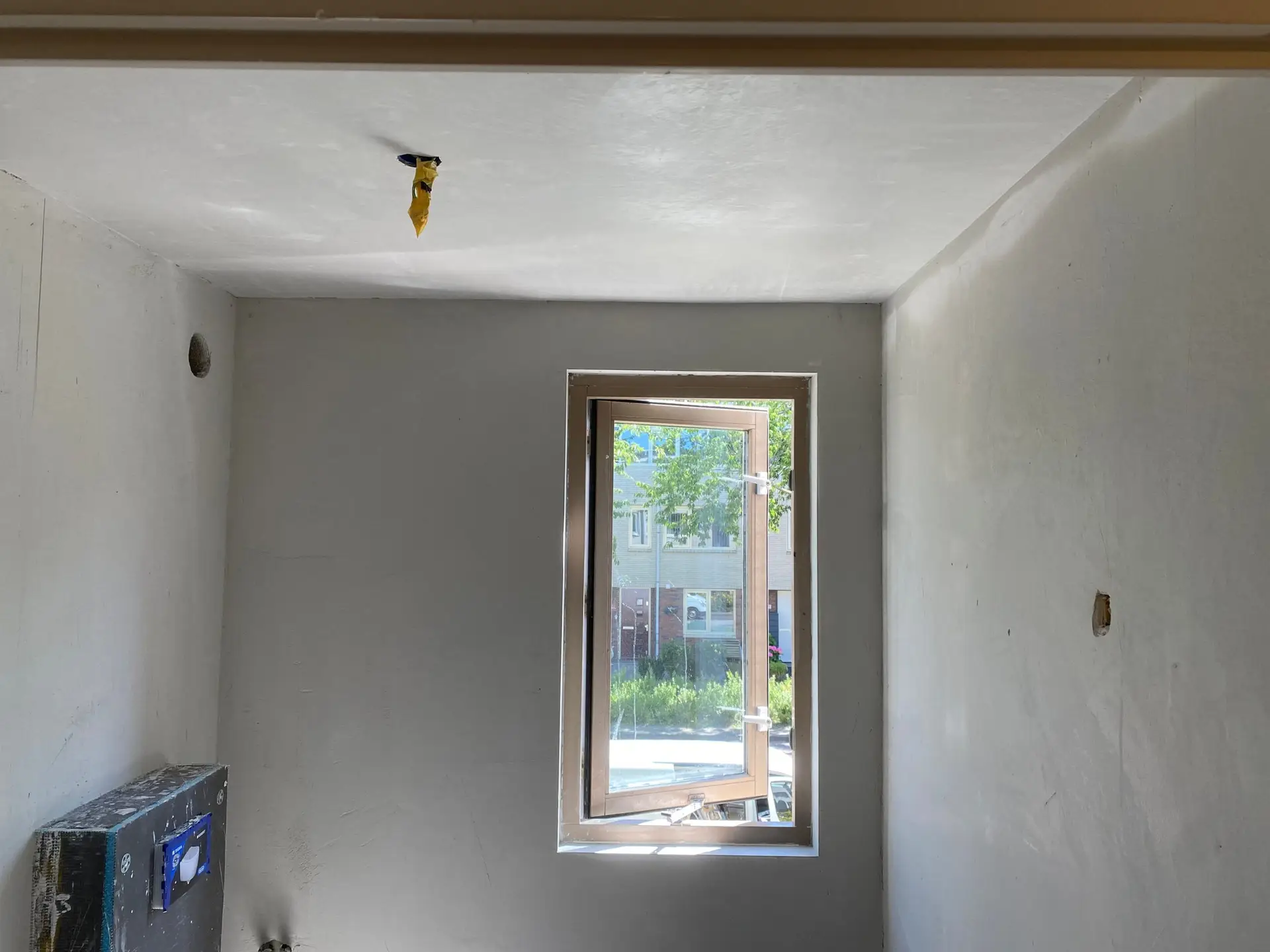 Vers gepleisterde slaapkamer met strak afgewerkte muren rond het raam